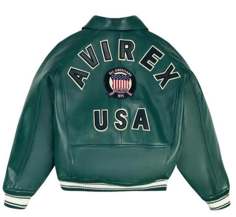 Może przedstawiać: Ciemnozielona sk&oacute;rzana kurtka z białymi wykończeniami. Z tyłu napis "AVIREX" w łuku, poniżej "USA" oraz okrągła naszywka z amerykańską flagą. Klasyczny styl bomberki.