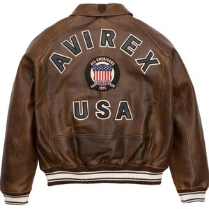 May include: Brown leather jacket with the word "AVIREX" across the shoulders and "USA" at the bottom. A circular patch with the American flag and the words "ALL AMERICANS ESTABLISHED 1975" is centered. The jacket has a ribbed white and brown striped hem.