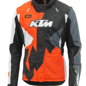 May include: A motorcycle jacket featuring a bold color-blocked design in orange, black, white, and gray. The front displays the white KTM logo across the chest. The jacket includes a high collar, long sleeves, and adjustable side straps for fit.
