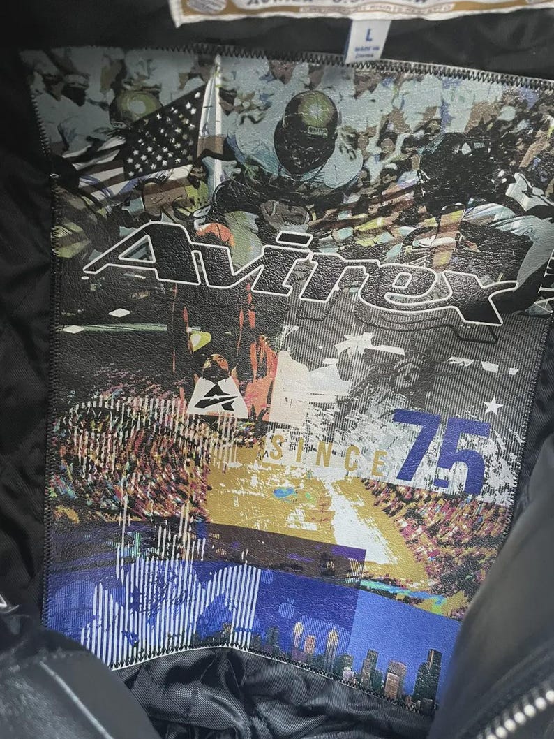 May include: Black leather jacket with a large graphic on the back featuring the word "Avirex" in white, a football scene, the American flag, and the text "Since 75". The jacket is labeled size L.