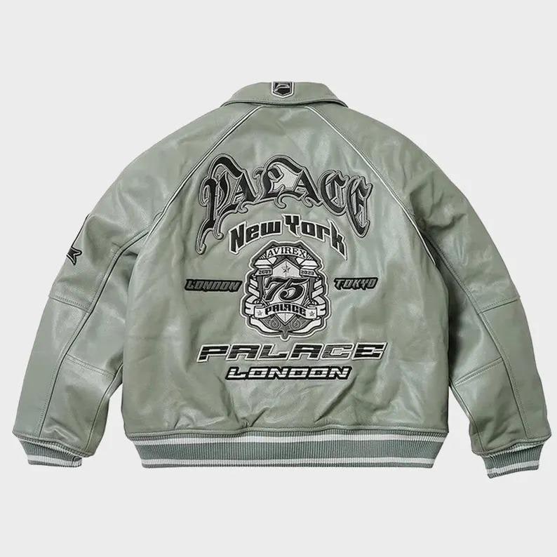 May include: A light green leather jacket with a classic collar and ribbed cuffs. The back features the text "PALACE New York" in a stylized font, along with additional text and emblems. The jacket has a white stripe detail.