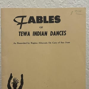 May include: A softcover book titled Fables of Tewa Indian Dances, as recorded by Regina Albarado De Cata of San Juan. The beige cover features black ink illustrations of a person with arms raised and a coiled snake, with bold black text.