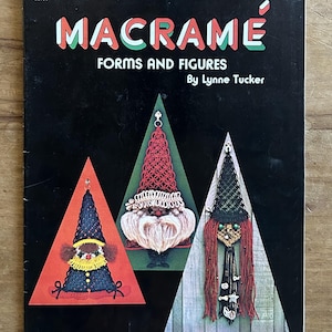 May include: A black instructional book titled MACRAMÉ FORMS AND FIGURES by Lynne Tucker. The cover features three triangular graphic panels displaying macramé figures: a blue figure with a yellow collar, a red figure with a white beard, and a black figure with long red hair.