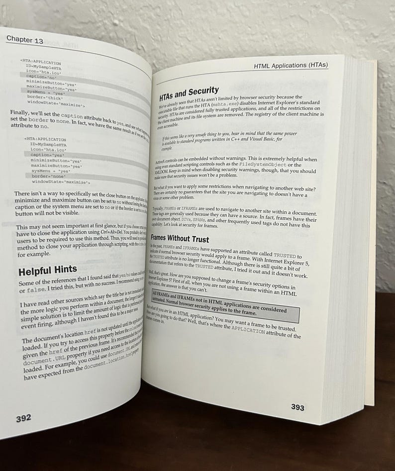 May include: An open technical book showing pages 392 and 393. The left page features code snippets for HTA applications, while the right page contains text under the heading HTML Applications (HTAs) and a section titled HTAs and Security.