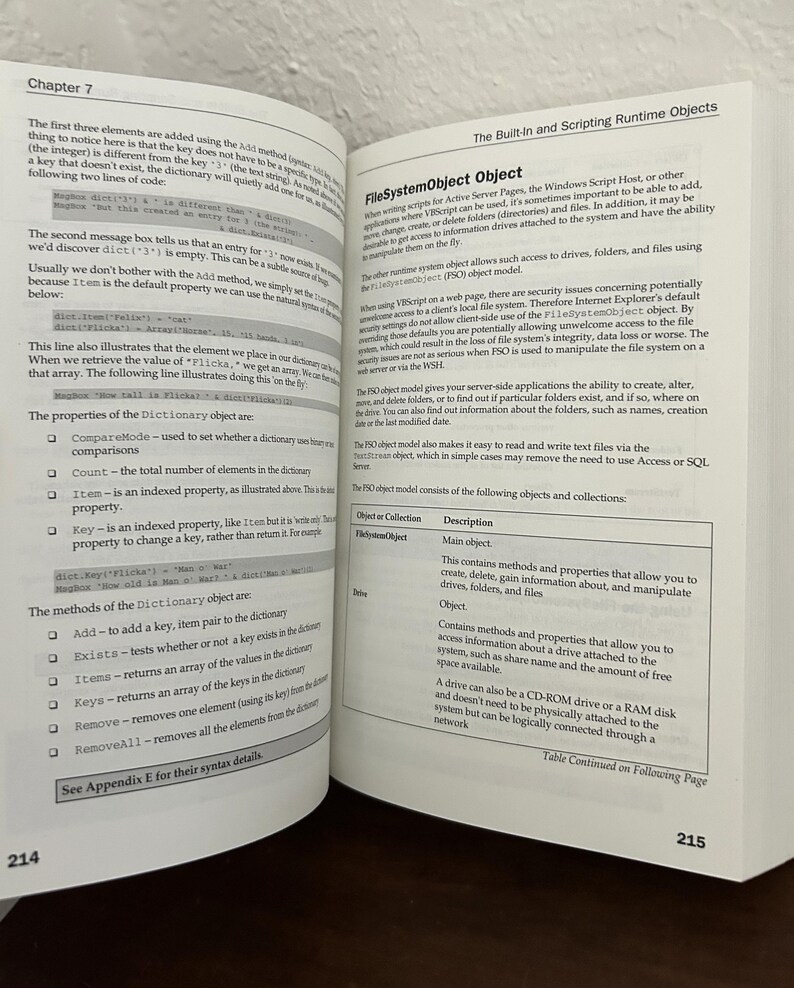 May include: An open technical textbook showing pages 214 and 215. The left page is titled Chapter 7 and discusses Dictionary object methods and properties. The right page covers the FileSystemObject object with a table of objects and descriptions.