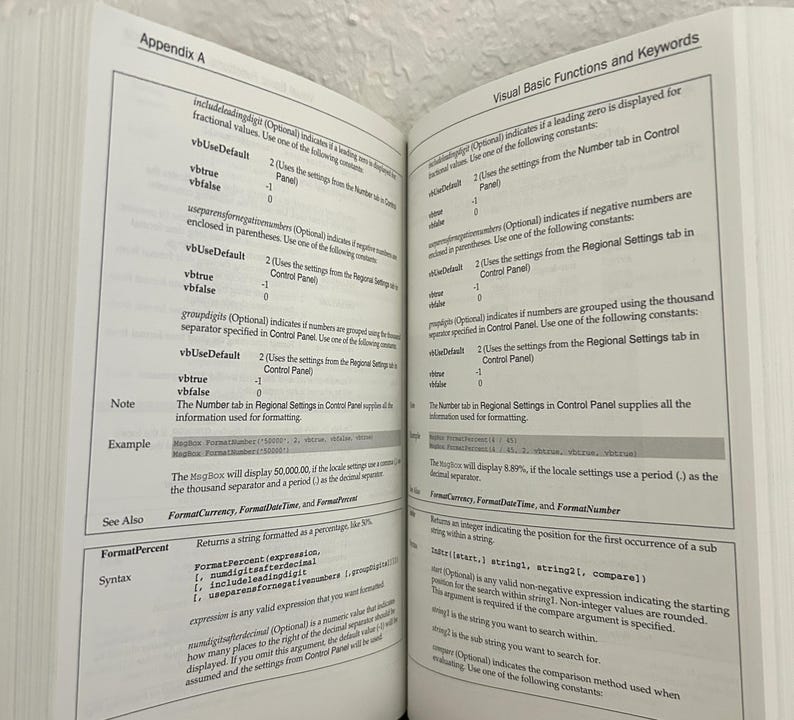 May include: An open technical book displaying Appendix A with Visual Basic Functions and Keywords. The pages contain black text on a white background, detailing syntax, constants, and examples for programming functions like FormatPercent.