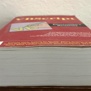 May include: A thick paperback book titled VBScript Programmer's Reference with a red cover. The cover features the text VBScript, a graphic of a hand writing with a pen, and a list of authors including Suzanne Clark and Antonio De Donatis.