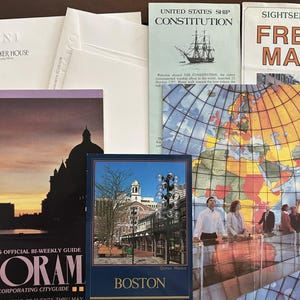 May include: A collection of travel brochures and maps. Includes a brochure for the Omni Parker House hotel, a map of Europe, and a brochure for the USS Constitution. Other brochures include "Boston's Official Bi-Weekly Guide" and a Boston travel guide.