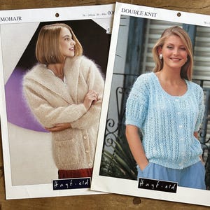 May include: Two Hayfield knitting pattern leaflets. The left leaflet features a beige mohair cardigan with a shawl collar and front buttons. The right leaflet displays a light blue short-sleeved double knit button-up top with a textured pattern.