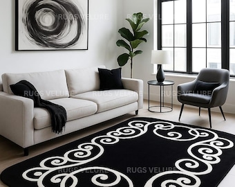 May include: A black rectangular rug with a white scroll design in a living room setting. The rug is placed in front of a light-colored sofa and a large window. The room also features a black and white abstract painting.