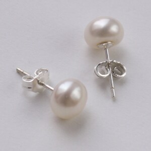 May include: A pair of pearl stud earrings with silver posts and butterfly backs.