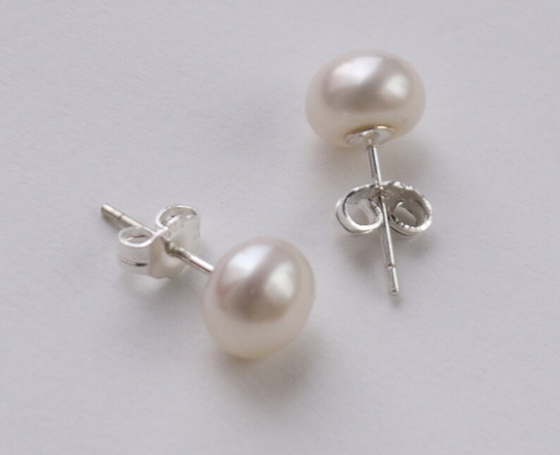 May include: A pair of pearl stud earrings with silver posts and butterfly backs.