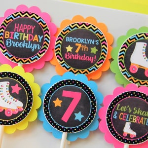 May include: Six circular cupcake toppers with scalloped edges in neon pink, orange, lime green, yellow, and blue. The designs feature black backgrounds with colorful roller skates, stars, and text including Happy Birthday Brooklyn and Let's Skate.