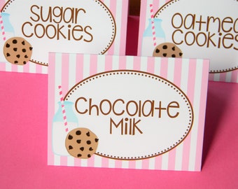 May include: Three pink and white striped signs with brown text and illustrations. The signs read "Sugar Cookies", "Oatmeal Cookies", and "Chocolate Milk". Each sign features a cartoon milk bottle with a straw and a chocolate chip cookie.