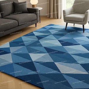 Puede incluir: Una alfombra geom&eacute;trica azul adorna el suelo. El dise&ntilde;o de la alfombra presenta una serie de rombos en varios tonos de azul, creando un estilo moderno. La alfombra est&aacute; colocada en un sal&oacute;n, a&ntilde;adiendo un toque de dise&ntilde;o.