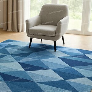 Puede incluir: Una alfombra geom&eacute;trica azul con un dise&ntilde;o de diamantes es el centro de atenci&oacute;n. Un sill&oacute;n gris claro descansa sobre la alfombra. El dise&ntilde;o de la alfombra presenta varios tonos de azul. La habitaci&oacute;n tiene suelo de madera.