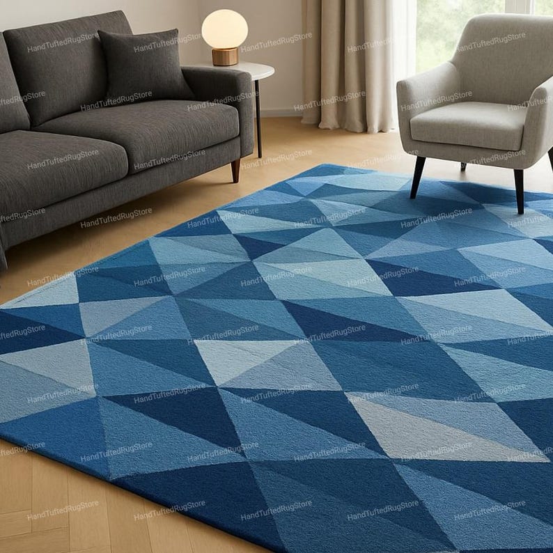 Puede incluir: Una alfombra geom&eacute;trica azul adorna el suelo. El dise&ntilde;o de la alfombra presenta una serie de rombos en varios tonos de azul, creando un estilo moderno. La alfombra est&aacute; colocada en un sal&oacute;n, a&ntilde;adiendo un toque de dise&ntilde;o.