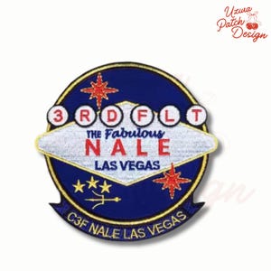 May include: Embroidered patch with a blue and gold border, featuring the text "3RD FLT" and "THE FABULOUS NALE LAS VEGAS." The design includes red stars and a stylized white sign. The patch also has the text "C3F NALE LAS VEGAS."