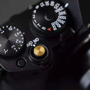 May include: A white ceramic mug with a black handle and the text "But First, Coffee" in a black, bold font. The mug is sitting on a wooden surface. The mug is approximately 4 inches tall.