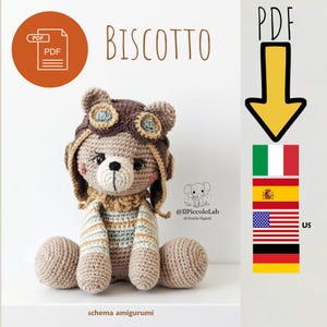 Può includere: Un orso amigurumi all'uncinetto che indossa un cappello da aviatore marrone con occhiali, un maglione a righe e un colletto a balze. L'immagine include il testo BISCOTTO, un'icona PDF, una freccia gialla e le bandiere di Italia, Spagna, USA e Germania.