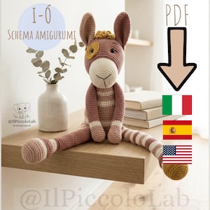 Può includere: Un giocattolo asino amigurumi all'uncinetto con corpo rosa polvere, muso color crema e una macchia gialla sopra un occhio. L'asino ha orecchie lunghe, un ciuffo di capelli gialli e zampe a righe. Il testo include I-Ó SCHEMA AMIGURUMI, PDF e tre bandiere.