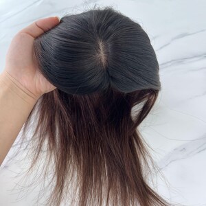 以下が含まれることがあります： 自然な分け目のダークブラウンのヘアートッパー。ヘアピースは、ダークブラウンのベースと、長く赤みがかった茶色のストランドが特徴です。薄毛にボリュームとカバー力を加えるように設計されています。