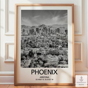 May include: Black and white framed print of the Phoenix, Arizona skyline. The print includes the city name, state, and coordinates. The image shows a cityscape with mountains in the background.