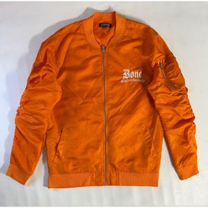 May include: Bright orange bomber jacket with a ribbed collar, cuffs, and hem. The jacket features a zipper closure and a small pocket on the left sleeve. The word "Bone" is embroidered on the chest in white script, with "thugs-n-harmony" below.