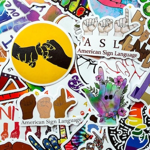 Puede incluir: Una colección de pegatinas con temas de lengua de signos americana. Los diseños incluyen manos formando las letras A, S y L, un signo de mano para el amor con detalles florales y una pegatina circular amarilla que muestra dos siluetas entrelazadas.