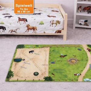 Può includere: Una scena di cameretta per bambini con un tappeto gioco e biancheria da letto a tema cavalli. Il tappeto gioco raffigura un'arena e un pascolo. La biancheria da letto ha uno sfondo bianco con illustrazioni di cavalli. Il testo "Spielwelt To Go" è visibile, 90 x 60 cm.