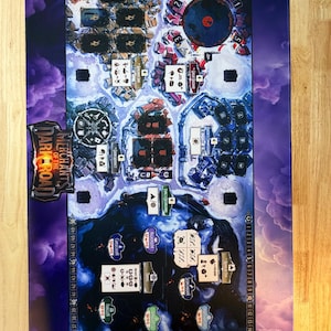 May include: A rectangular board game mat titled Merchants of the Dark Road with a purple cloud border. The surface features a detailed map with various locations, card slots, and a numbered track from 1 to 50 along the left and right edges.