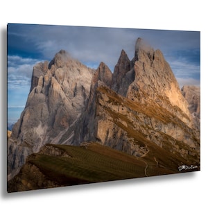 Puede incluir: Fotografía de paisaje de imponentes picos montañosos bajo un cielo nublado. Las montañas son una mezcla de gris y marrón, con zonas de vegetación verde en las laderas inferiores. El cielo es una mezcla de azul y gris.