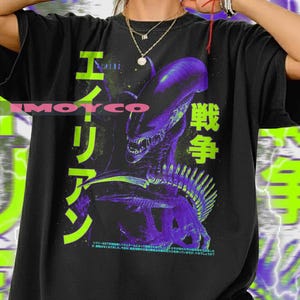 May include: Black t-shirt with a purple and green alien graphic and Japanese text. The design includes the word "ALIENS" in English and Japanese characters. The shirt has a crew neck and short sleeves.