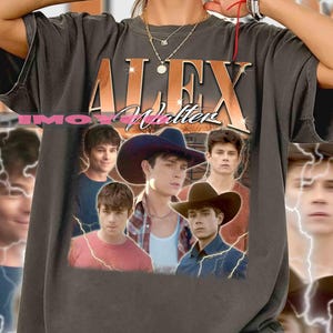 May include: Dark grey t-shirt with the gold text "ALEX Walter" above a collage of five young men. The shirt has a vintage, worn appearance.