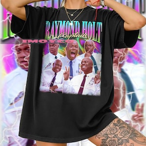 May include: Black t-shirt featuring a colorful graphic of Raymond Holt, with the text "RAYMOND HOLT Captain" in a retro font. The graphic includes multiple images of the character. The shirt is a relaxed fit.