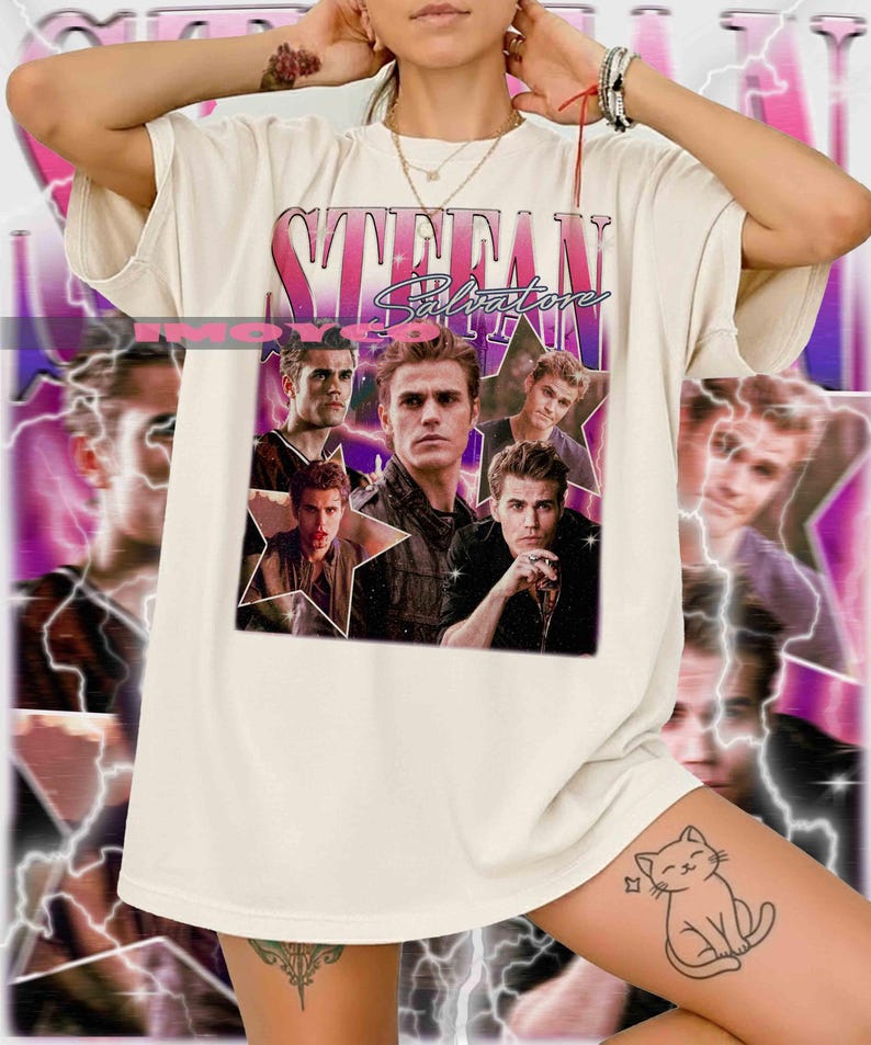 May include: Cream-colored t-shirt featuring a graphic of a man's face with the name "STEFAN" in a pink and purple retro font. The shirt has a vintage aesthetic, with multiple images of the man in various poses. The overall design is a collage style.