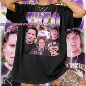 May include: Black t-shirt with a graphic featuring the word "THEO" in purple and white, and images of several people. The background has a purple and white lightning bolt design.