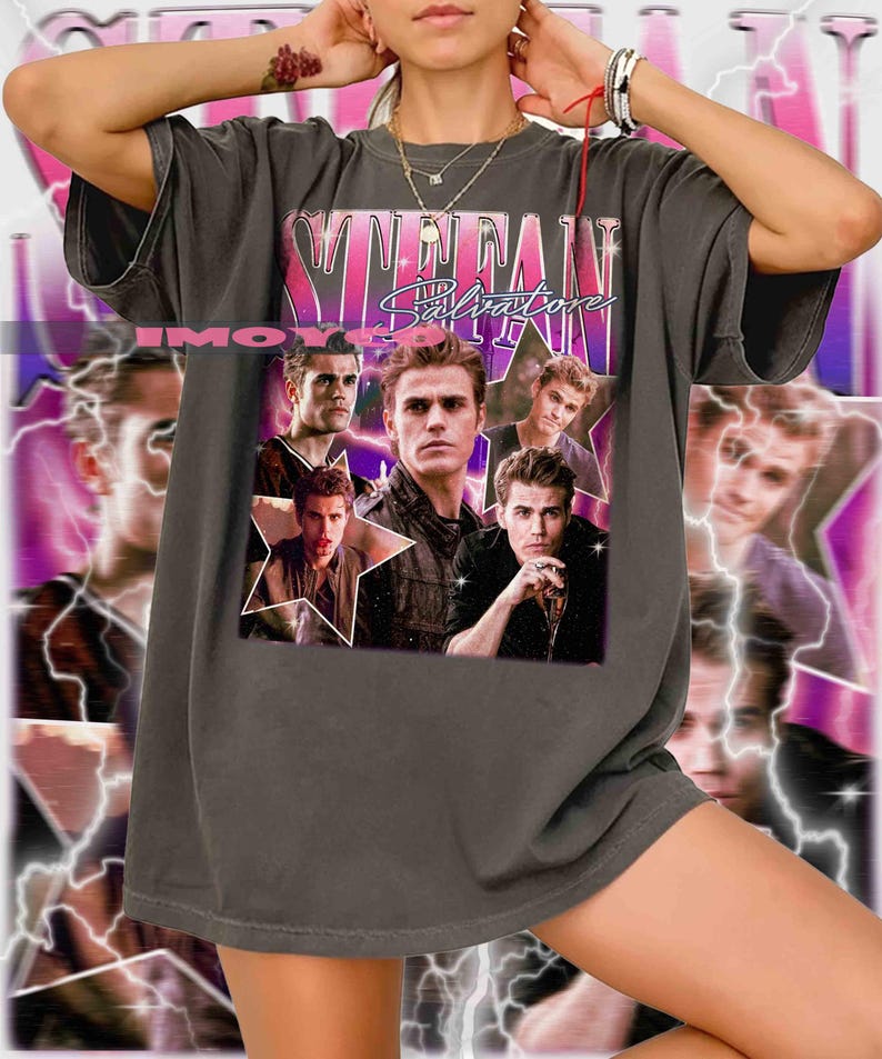 May include: Dark gray t-shirt featuring a collage of images and the text "Stefan Salvatore" in a pink and white design. The shirt has a vintage aesthetic and a relaxed fit.