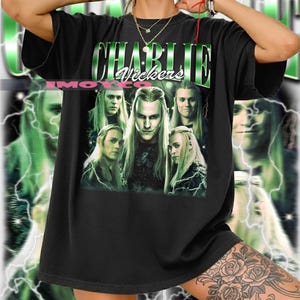 Könnte beinhalten: Schwarzes T-Shirt mit dem Namen "Charlie Vickers" in Grün, im Vintage-Stil. Das Shirt zeigt eine Collage von Bildern einer Person mit langen blonden Haaren. Der Hintergrund hat einen grünen Blitzeffekt.