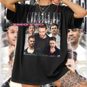 Könnte beinhalten: Schwarzes T-Shirt mit einem Aufdruck von mehreren Männern und dem Text "Charlie Vickers" in einer stilisierten Schrift. Das T-Shirt hat einen leicht verwaschenen Look. Der Hintergrund zeigt verschwommene Bilder und Blitze.