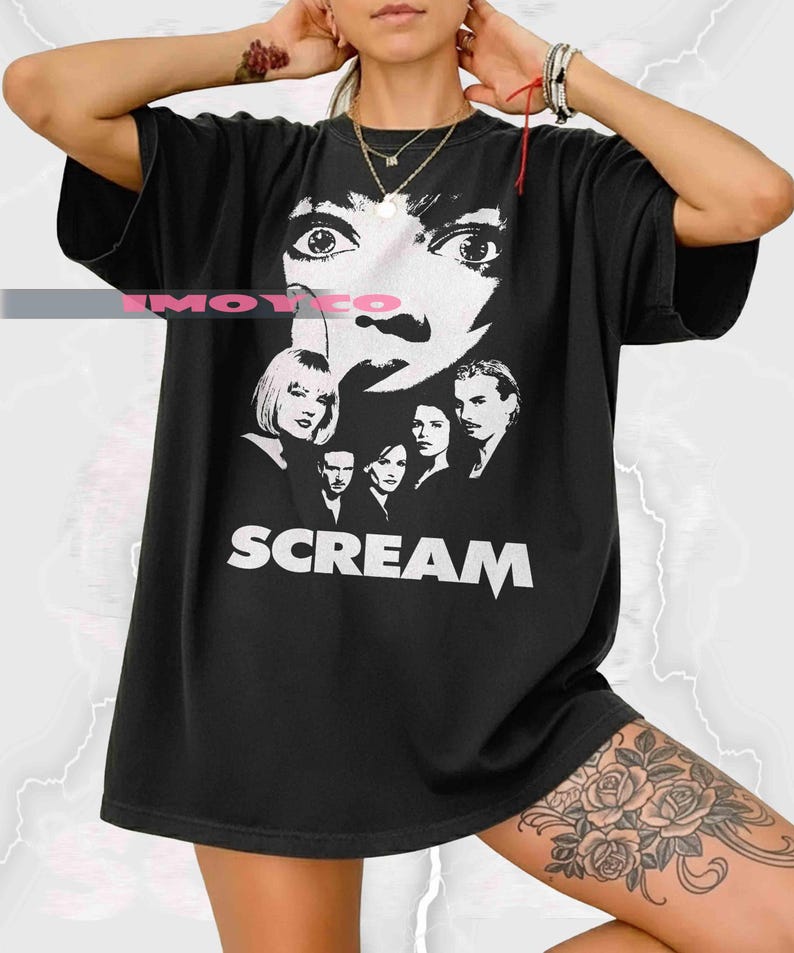 May include: Black t-shirt featuring a white graphic of a face and a group of people, with the word "SCREAM" in bold white letters. The shirt is a classic crew neck style.