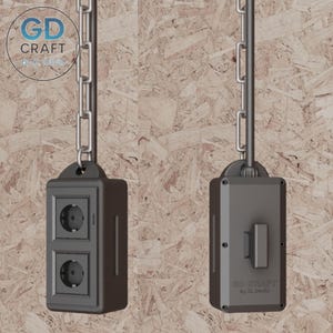Puede incluir: Dos enchufes eléctricos de color gris oscuro, cada uno con dos enchufes, colgados de una cadena plateada. Los enchufes rectangulares tienen un diseño moderno. El fondo es un panel de madera marrón claro.
