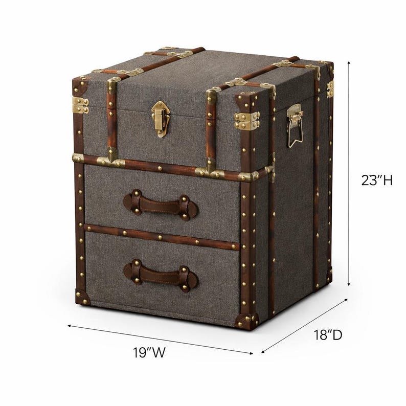 K&ouml;nnte beinhalten: Graue Aufbewahrungstruhe mit zwei Schubladen, 48 cm breit, 46 cm tief und 58 cm hoch. Sie hat braune Ledergriffe und -verzierungen, Messing-Ecken und einen Messingverschluss.