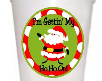 May include: White foam cup with a green, red, and white circular sticker. The sticker features a cartoon Santa Claus with the text "I'm Gettin' My Ho Ho Ho On!"
