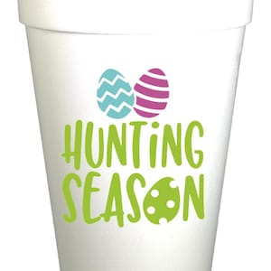 May include: A white foam cup with the words "HUNTING SEASON" in green, along with two Easter eggs in teal and purple. The cup is designed for Easter celebrations.