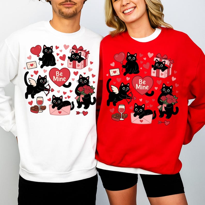 May include: White and red sweatshirts with a Valentine's Day theme. Each sweatshirt features a repeating pattern of black cat illustrations with hearts, gifts, and the text "Be Mine". The cats are depicted with wings, holding arrows, flowers, and balloons.