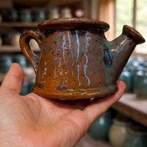 Può includere: Un set di tre tazze in ceramica con finitura opaca e macchiettata. Le tazze sono nei toni del crema, grigio chiaro e grigio scuro. Ogni tazza ha un design semplice e minimalista e un manico arrotondato.