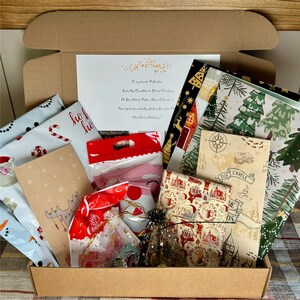 May include: A cardboard box filled with wrapped gifts and decorative paper. The gifts are wrapped in festive paper with Christmas and Harry Potter themes. The box contains a handwritten note and various small packages.