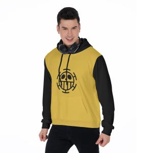 K&ouml;nnte beinhalten: Ein gelb-schwarzer Kapuzenpullover mit einer schwarzen Grafik auf der Vorderseite. Der Hoodie hat eine K&auml;ngurutasche und eine Kapuze mit Kordelzug. Die &Auml;rmel und die Kapuze sind schwarz, w&auml;hrend der K&ouml;rper gelb ist. Die Grafik ist ein stilisierter Totenkopf.