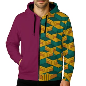 Puede incluir: Una sudadera con cremallera y diseño dividido. Un lado es burdeos liso, el otro presenta un patrón geométrico en tonos amarillos, verdes y marrones. La sudadera tiene una cremallera negra y una capucha con forro negro.